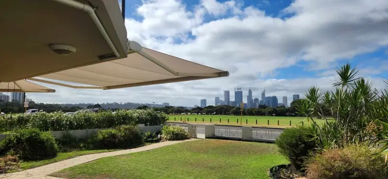 Folding arm awnings extended over a garden area with views of the South Perth skyline