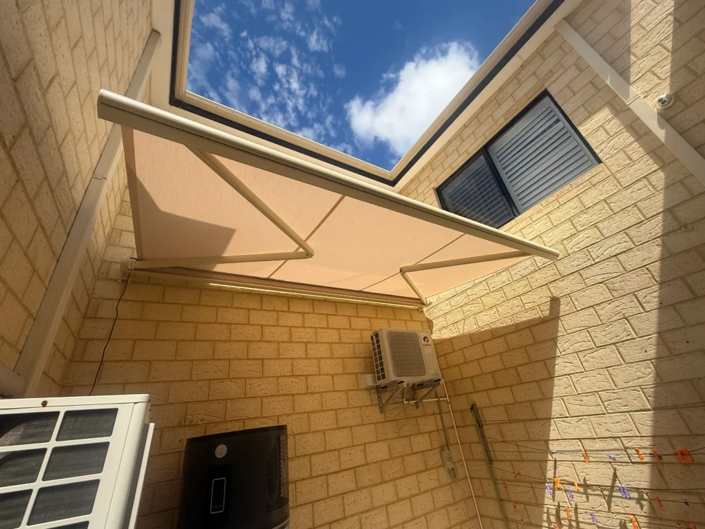 Motorised folding arm awning extended over a townhouse courtyard in Salter Point