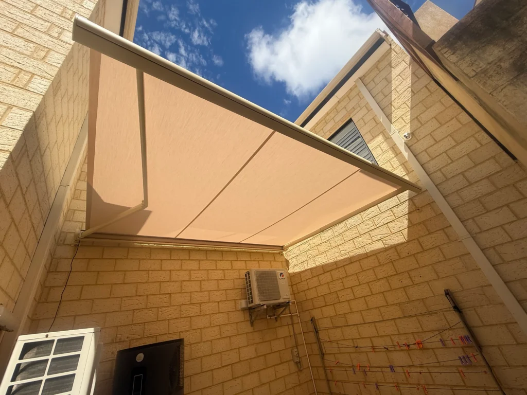 Sand coloured folding arm awning shading a high-walled courtyard in Salter Point