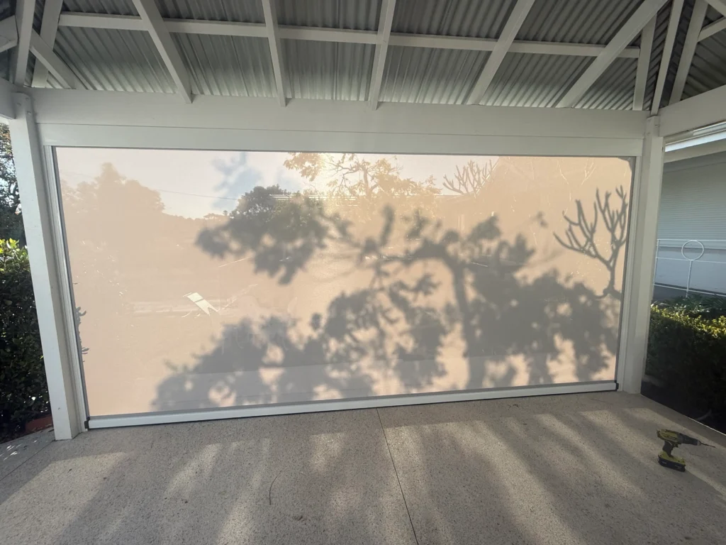 Motorised Ziptrak outdoor blind in Platinum mesh lowered inside a white garden pavilion in Beaconsfield
