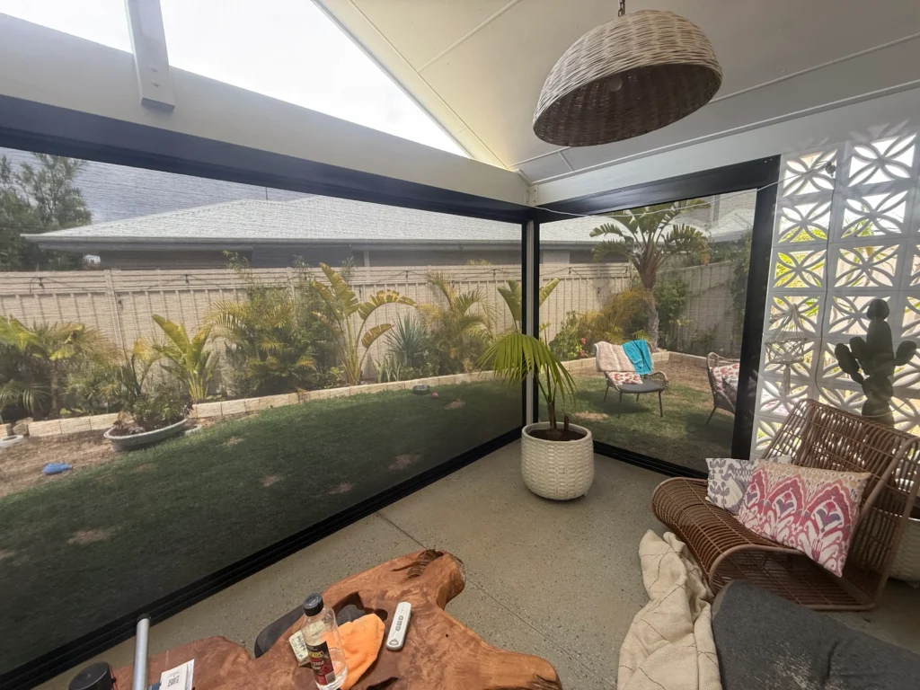 Inside a Safety Bay alfresco with black Ziptrak blinds lowered and the garden visible through the mesh