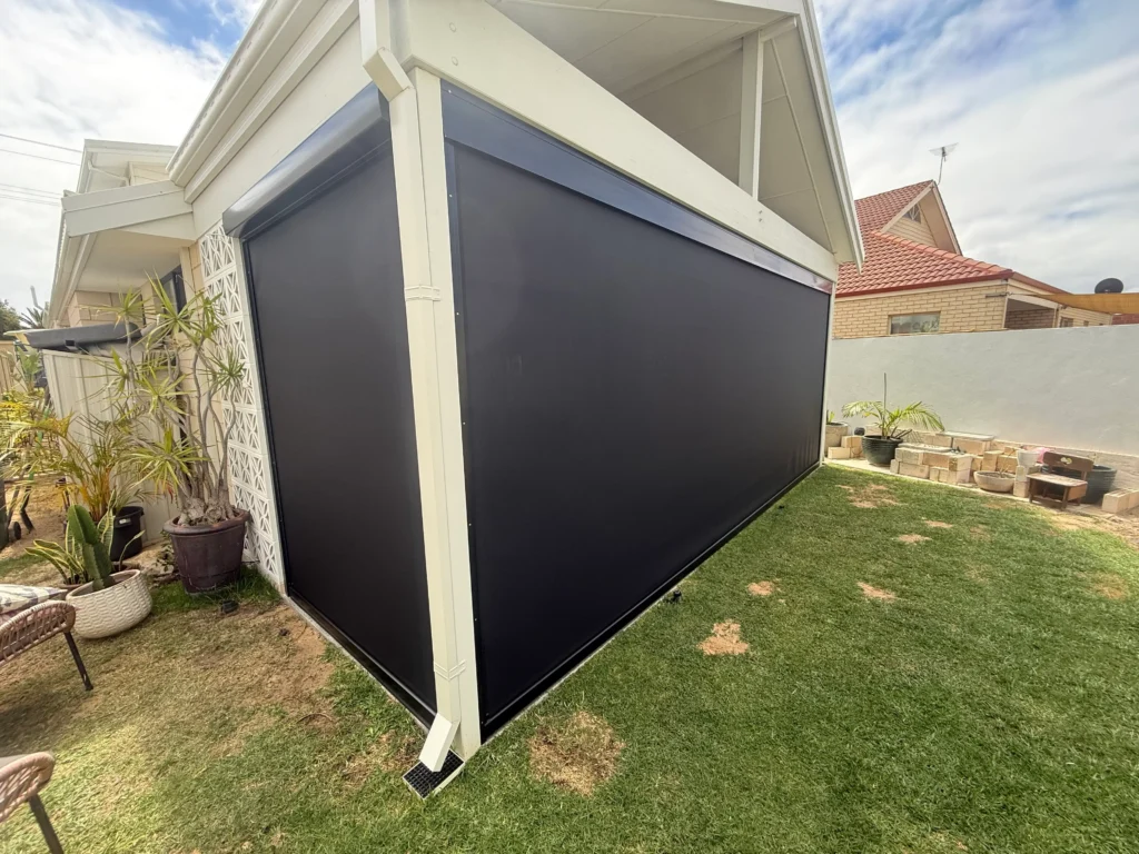 Exterior of a Safety Bay patio with black Ziptrak outdoor blinds lowered on two sides