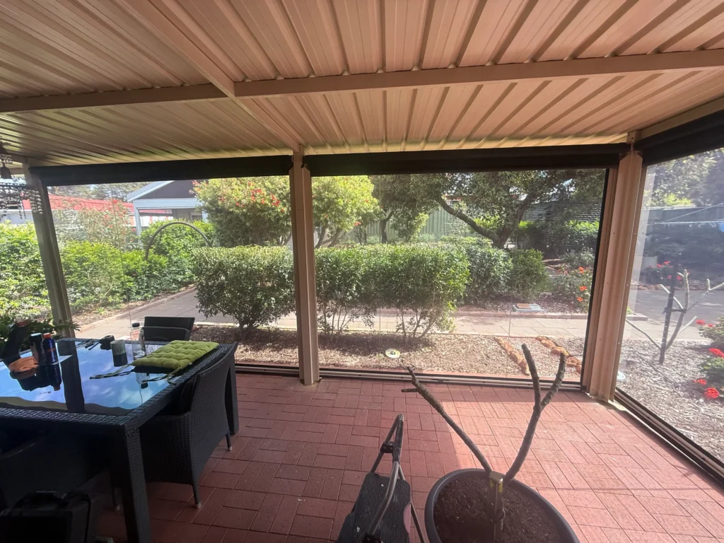 Tinted PVC Ziptrak blinds enclosing a patio dining area in Rivervale, viewed from inside