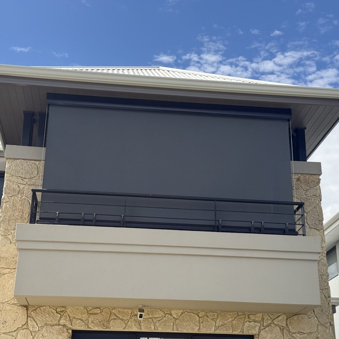 Exterior view of a cable guided outdoor blind fully lowered on a balcony